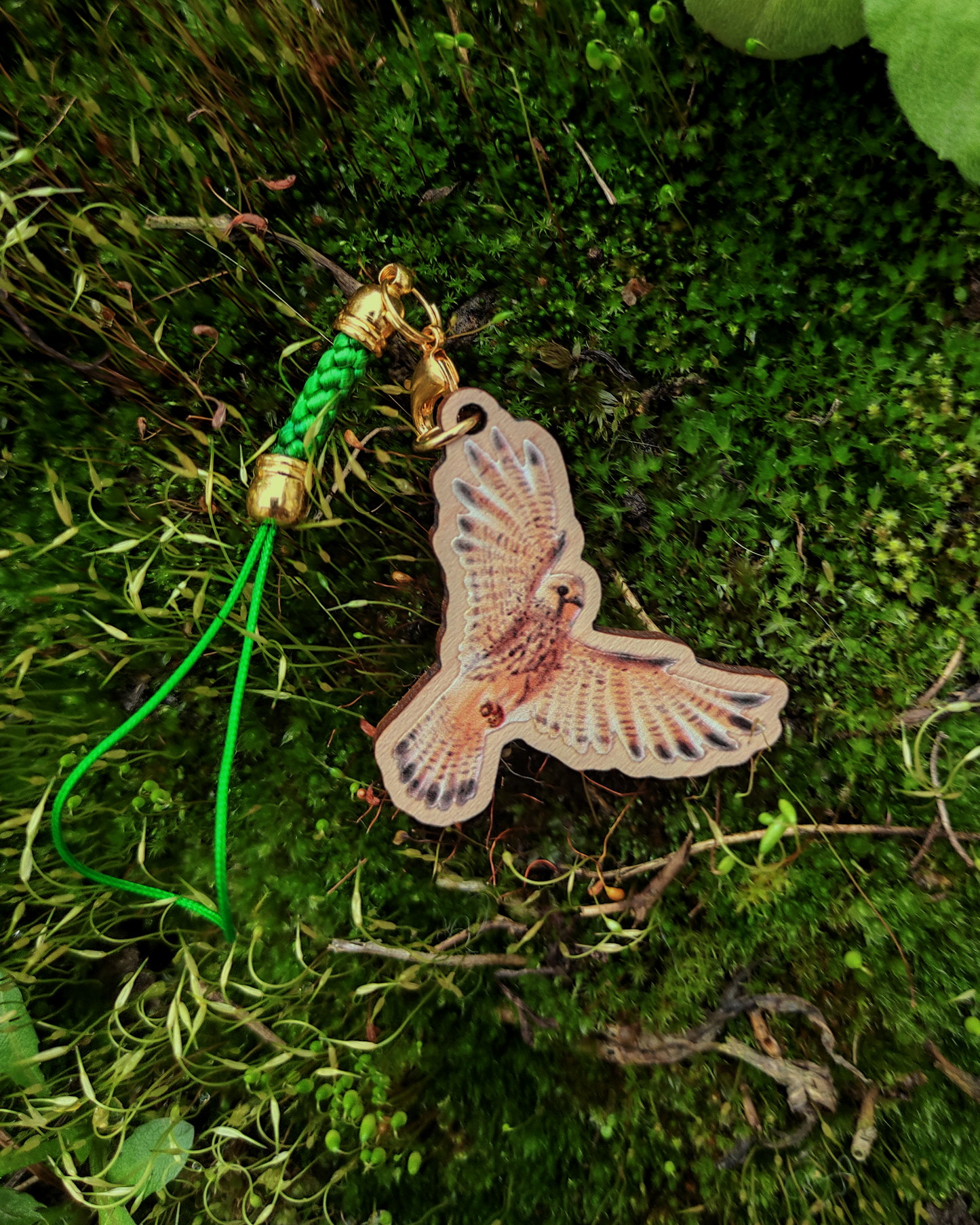 Wooden charm of a eurasian kestral on moss background.