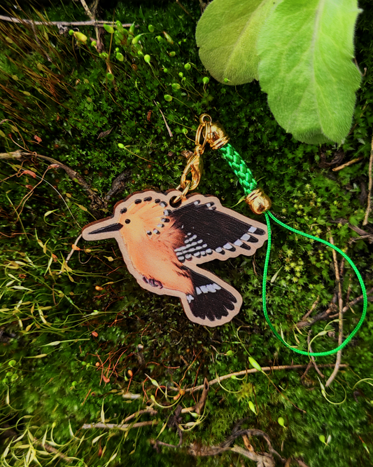 Wooden charm of a hoopoe on moss background.