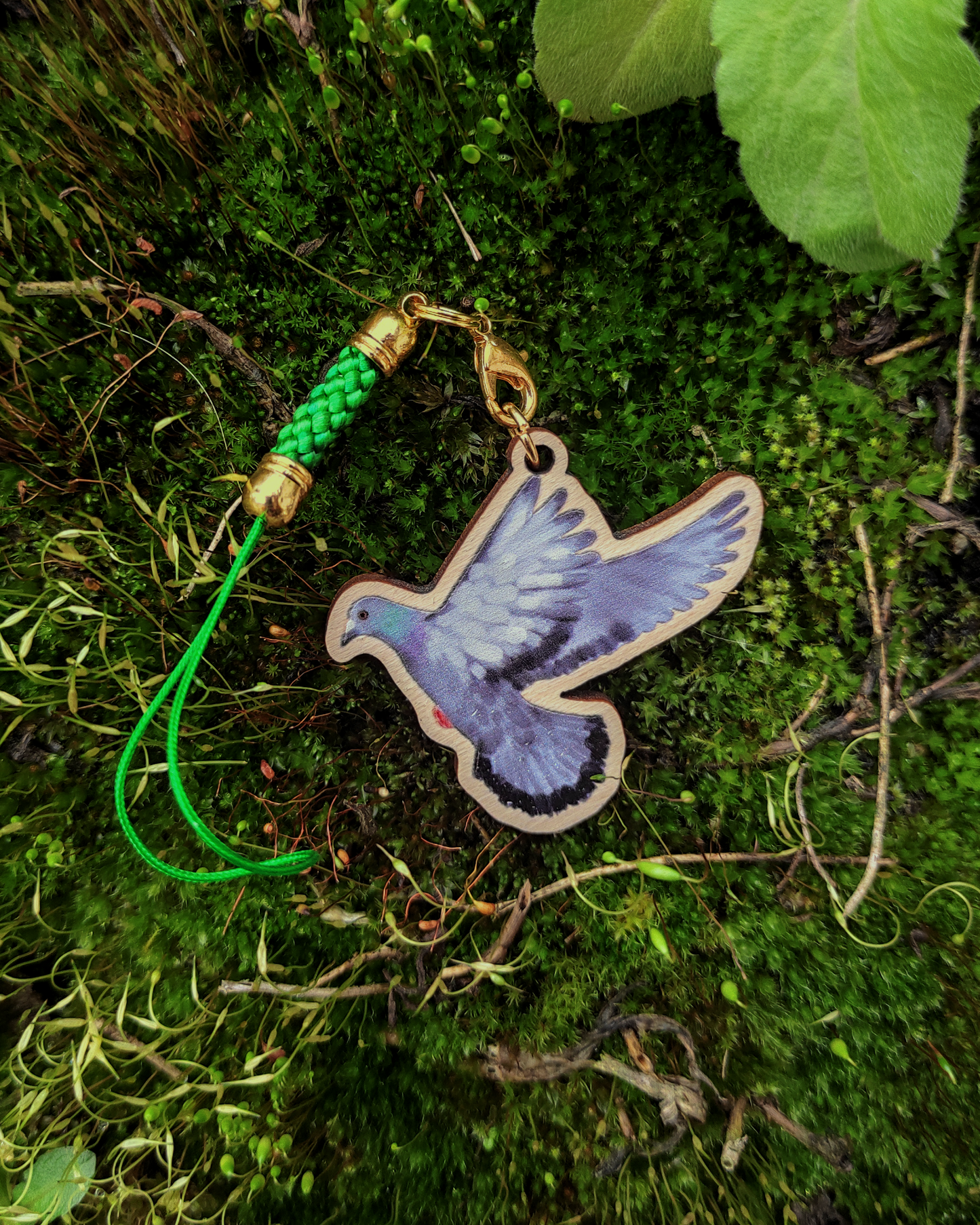 Wooden charm of a street pigeon on moss background.