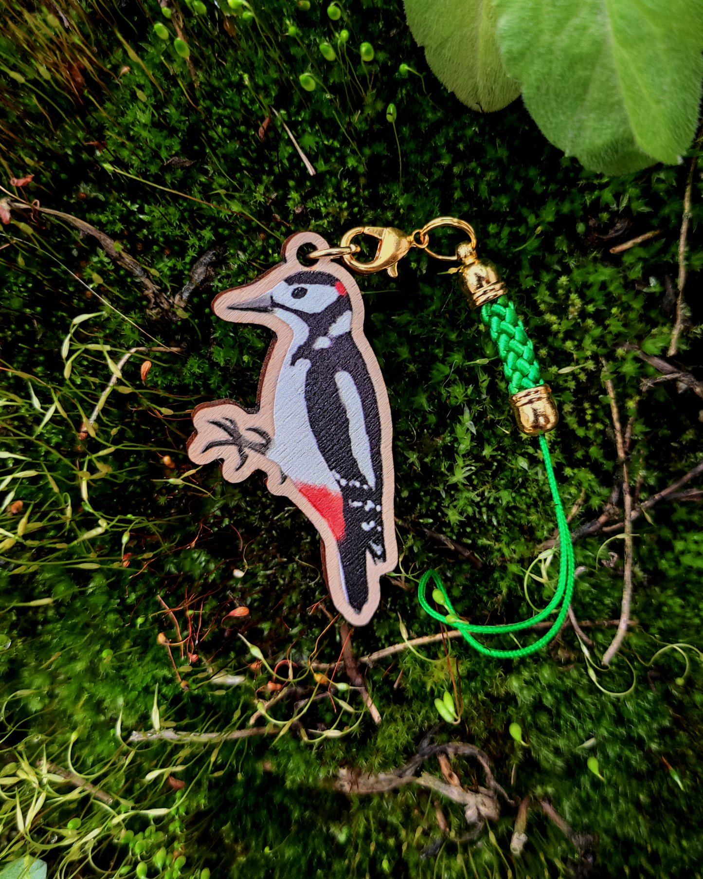 Wooden charm of a Great Spotted Woodpecker on mossy background.