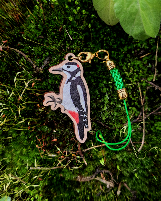 Wooden charm of a Great Spotted Woodpecker on mossy background.