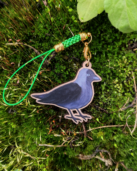 Wooden charm of a Jackdaw on mossy background.