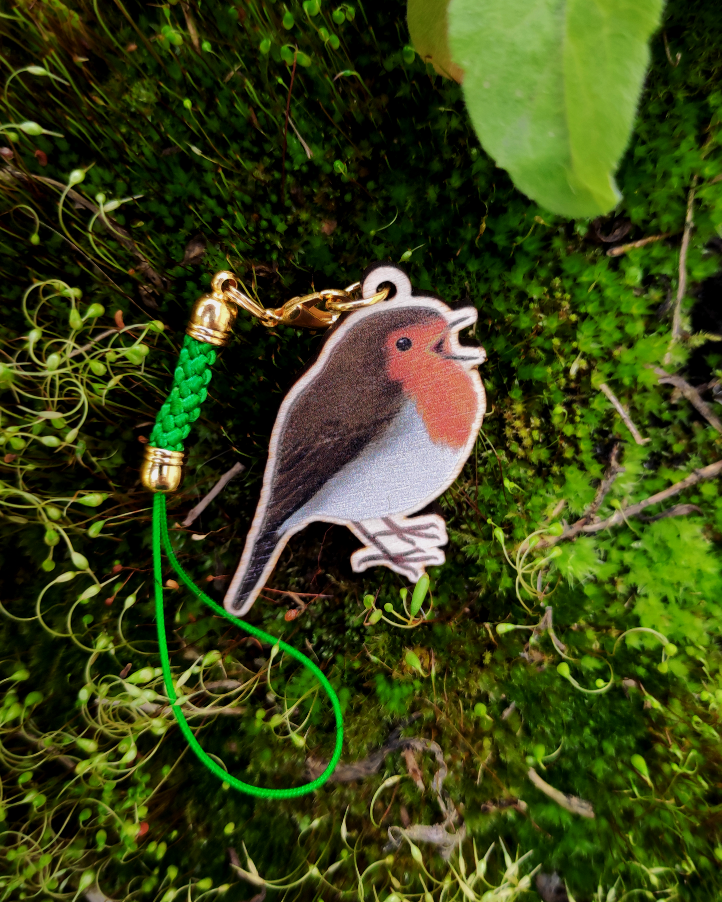 Wooden charm of a European Robin on mossy background.