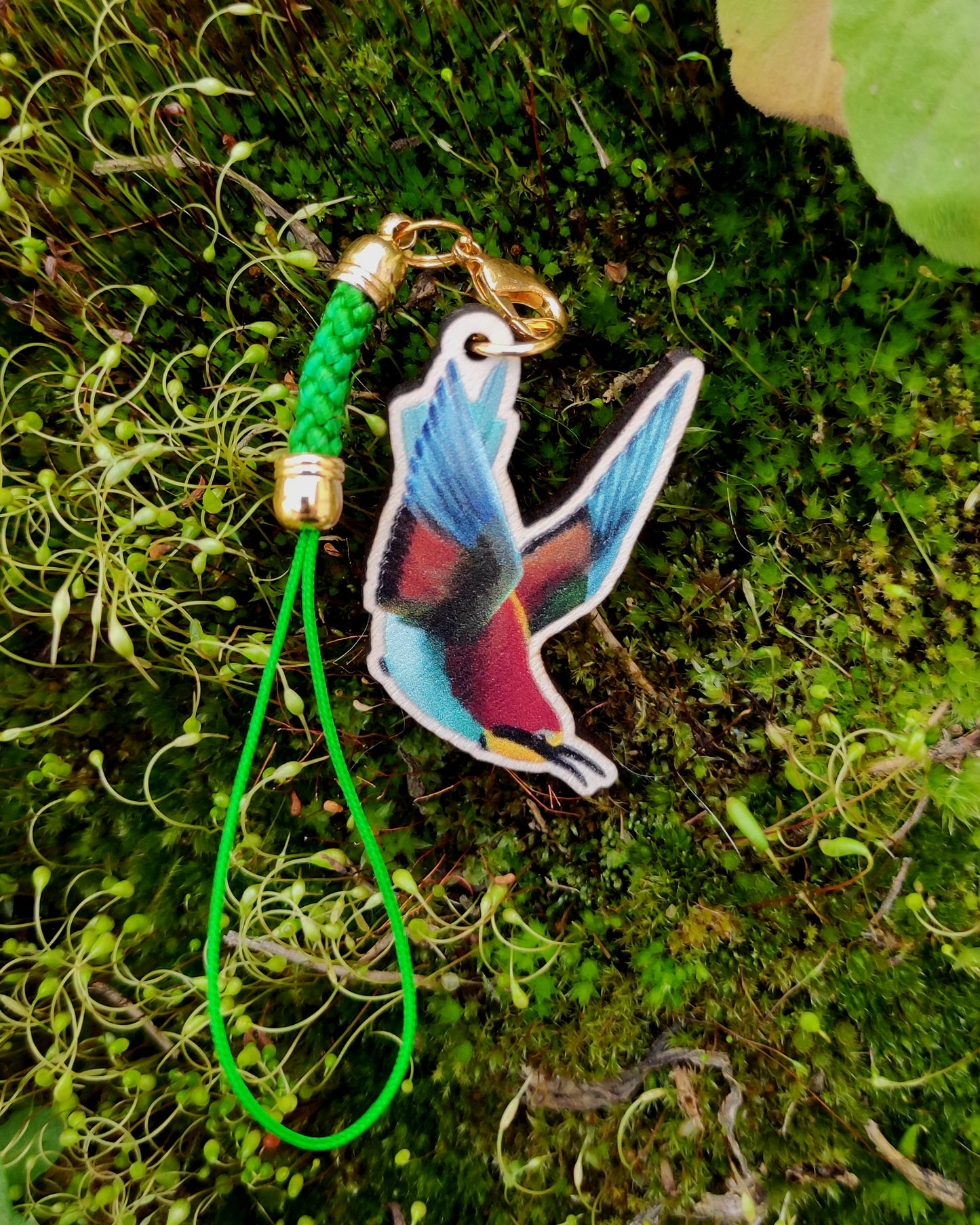 Wooden charm of a European Bee Eater on mossy background.