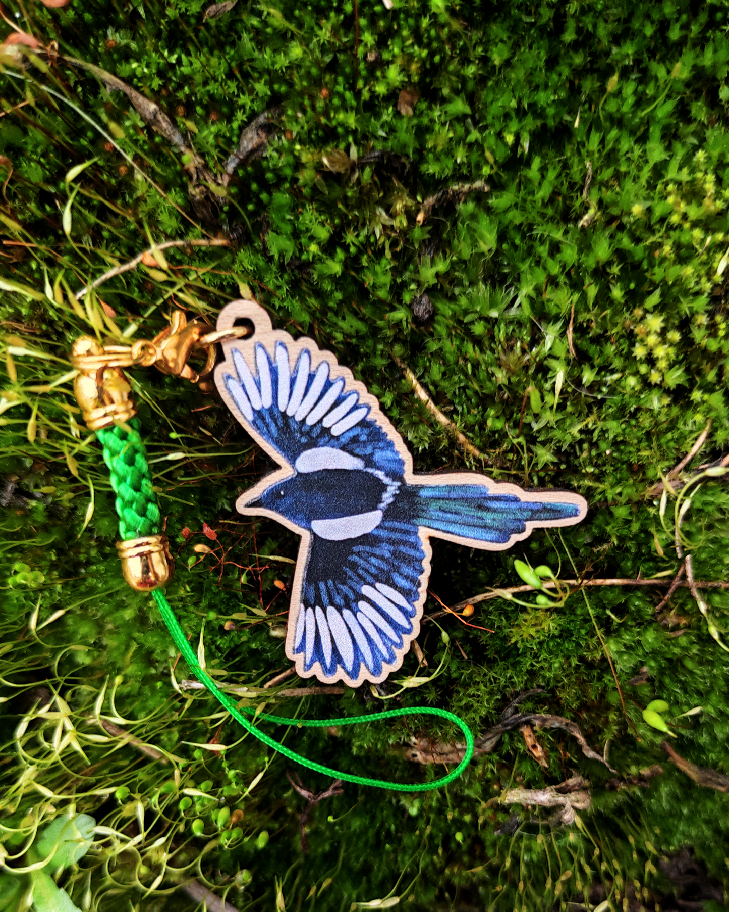 Wooden charm of a magpie on moss