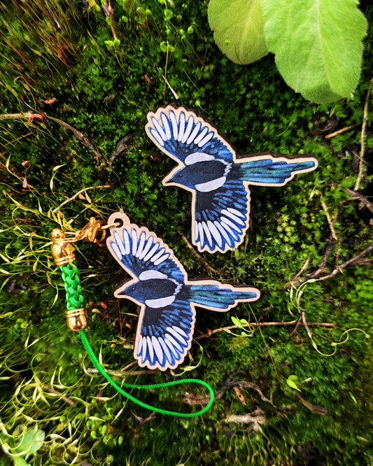 Wooden pin and charm of a magpie on moss