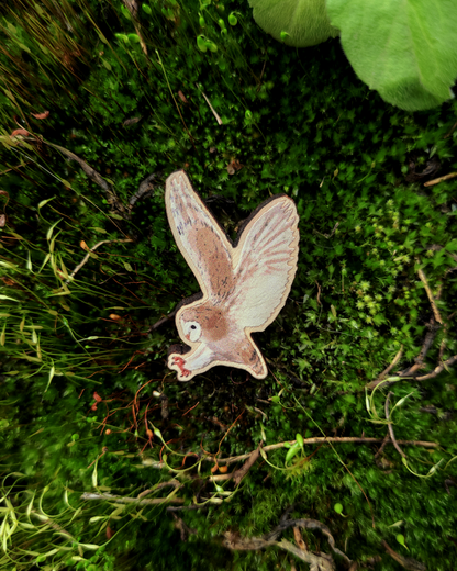 Wooden pin of a Barn Owl on mossy background.