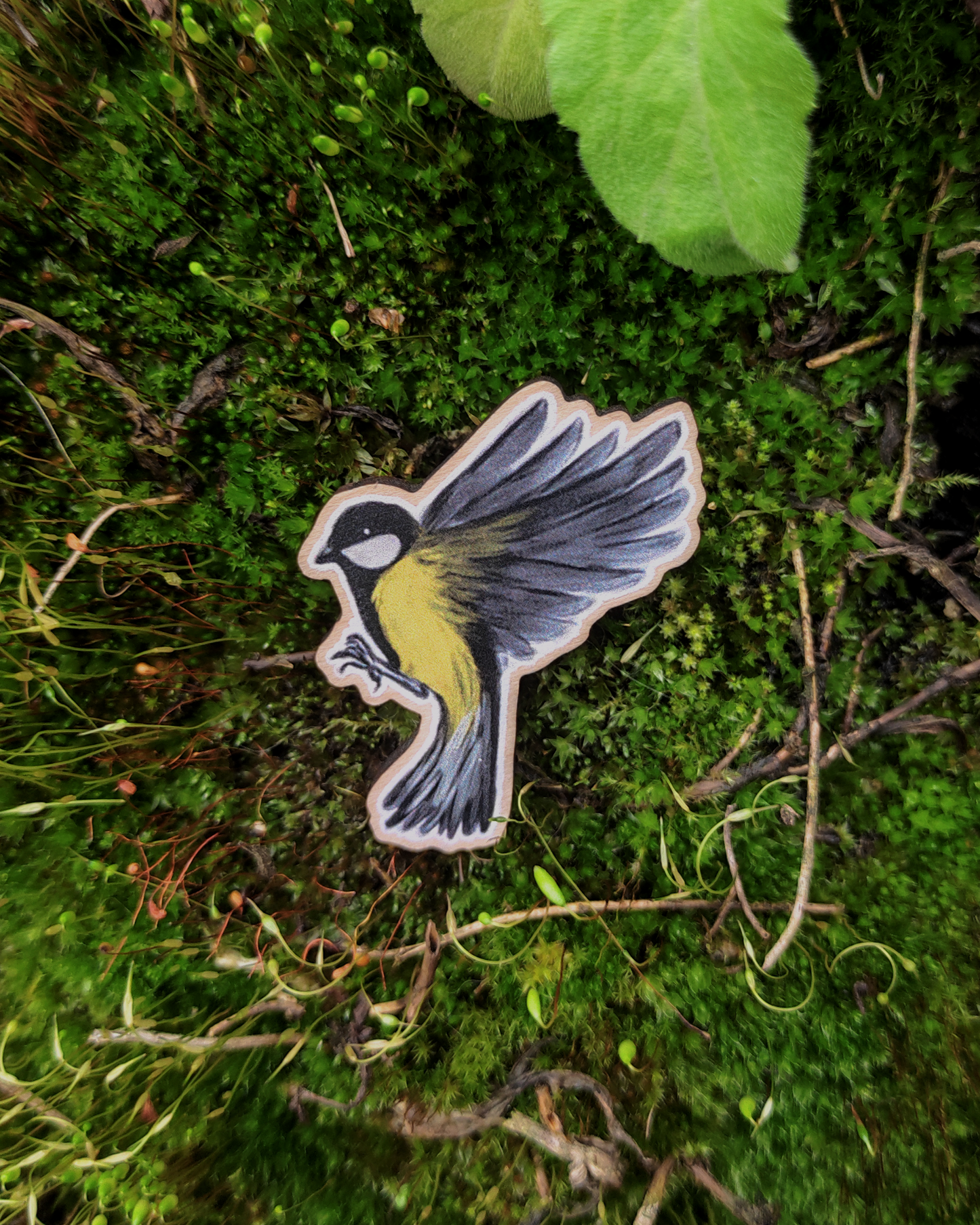 Wooden pin of a Great tit on mossy background.