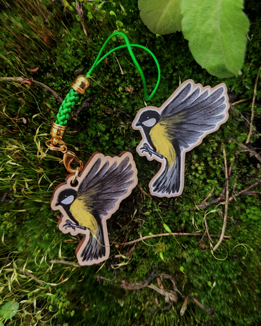 Wooden pin and charm of a Great tit on mossy background.