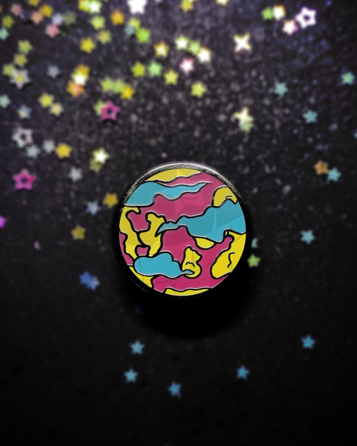 Hard enamel pin of a stylized planet on a dark, blurry background. The pin has the colors of the pansexual flag in it.