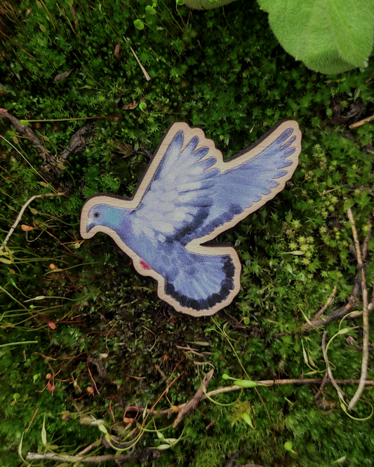 Wooden pin of a street pigeon on moss background.