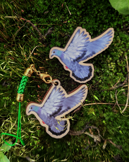 Wooden pin and charm of a street pigeon on moss background.