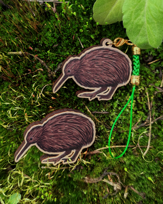Wooden pin and charm of a Kiwi on moss background.