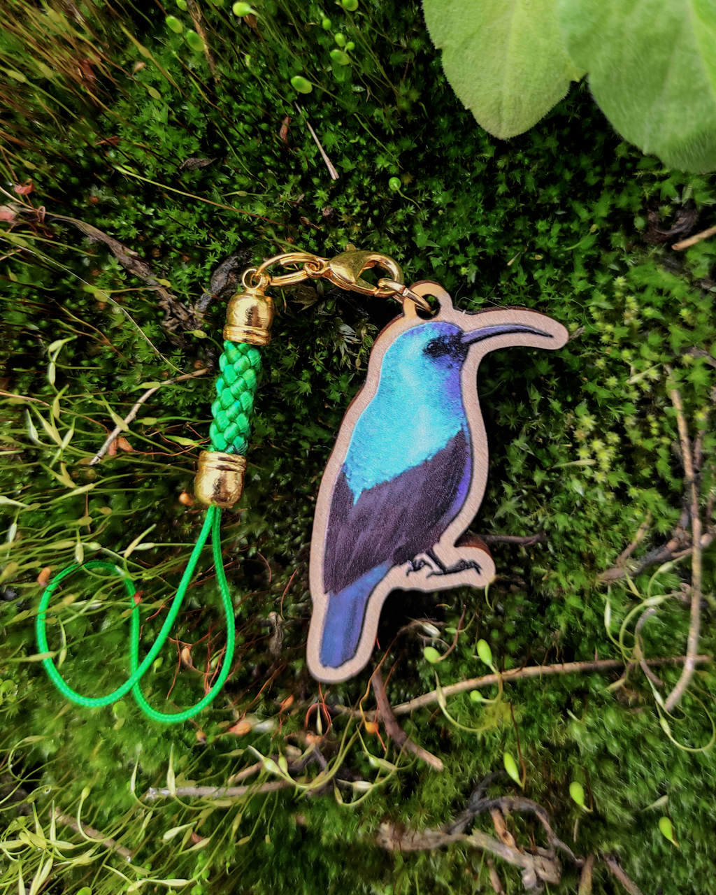 Wooden charm of a Palestine Sunbird on mossy background.