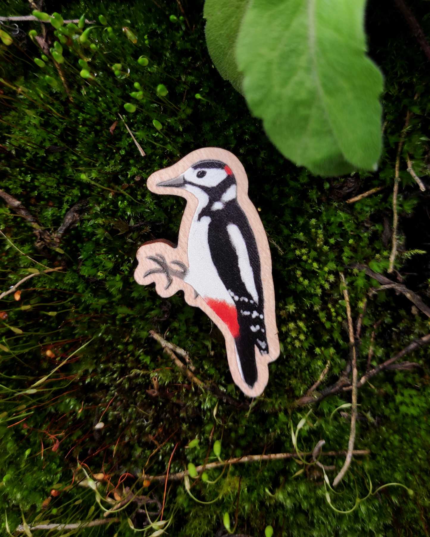 Wooden pin of a Great Spotted Woodpecker on mossy background.