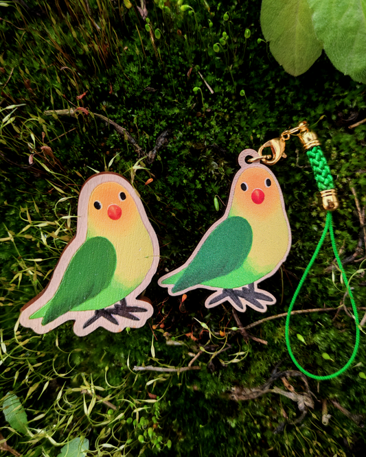 Wooden pin and charm of a Lovebird on mossy background.