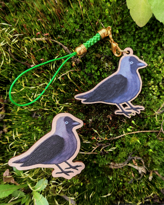 Wooden pin and charm of a Jackdaw on mossy background.