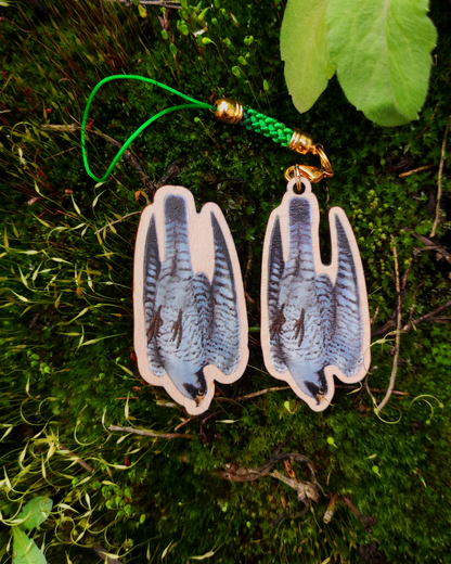 Wooden pin and charm of a Peregrine Falcon on mossy background.