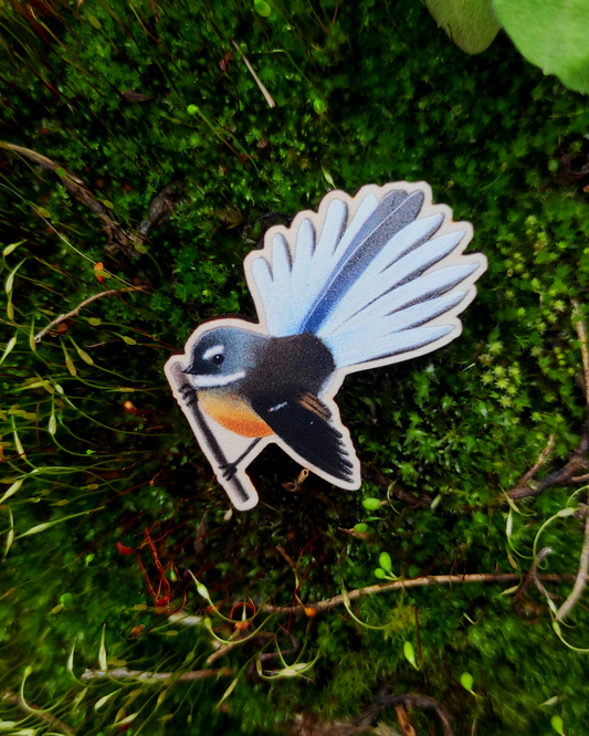 Wooden pin of a New Zealand Fantail on mossy background.