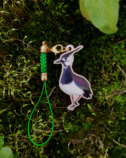 Wooden charm of a Northern Lapwing on mossy background.