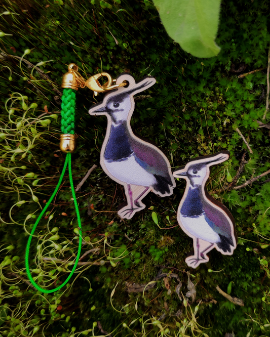 Wooden pin and charm of a Northern Lapwing on mossy background.