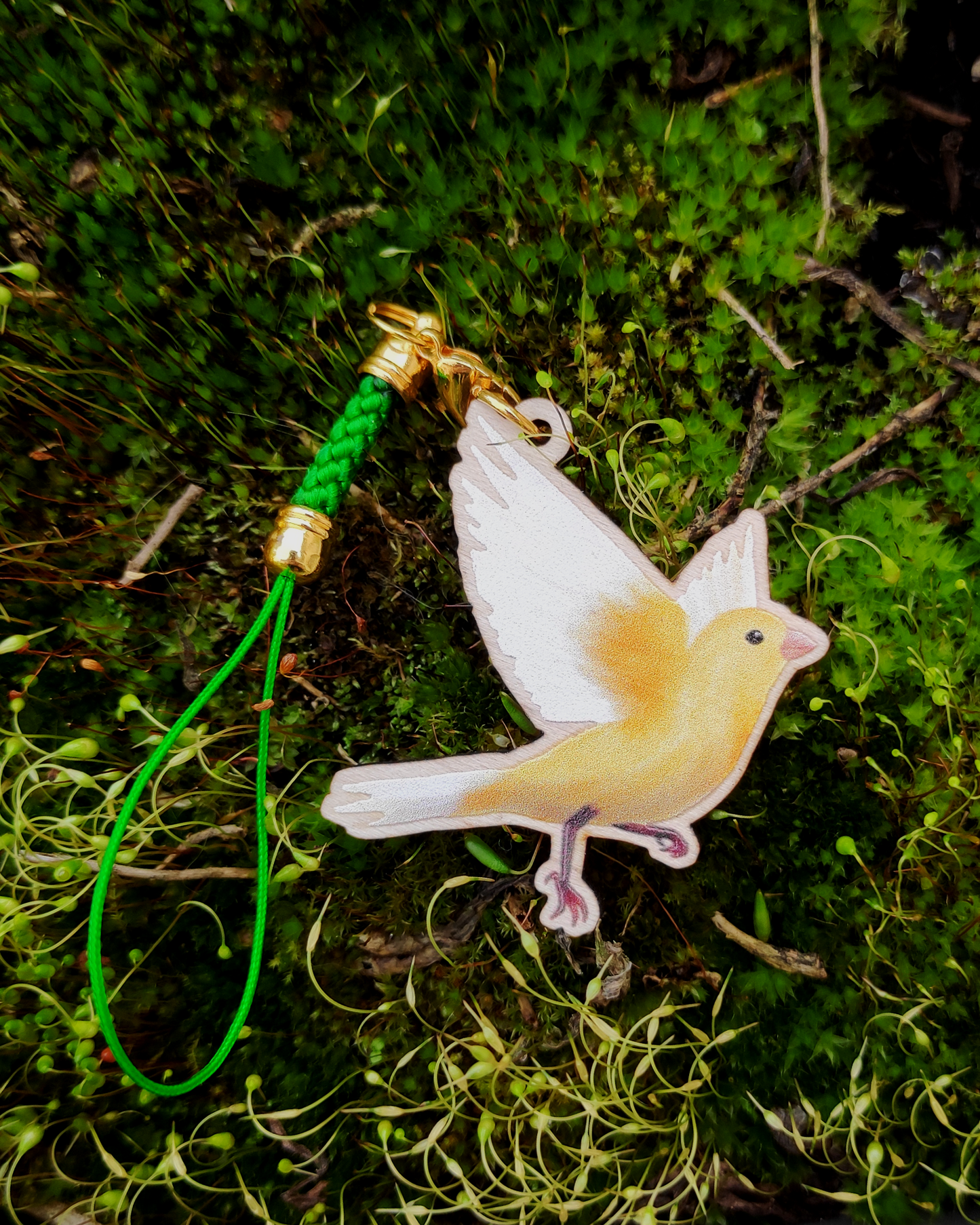 Wooden charm of a Canary on mossy background.