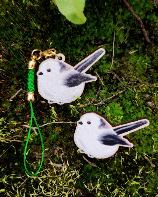 Wooden pin and charm of a Long-tailed tit on mossy background.