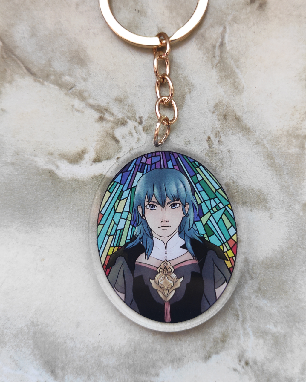 Keychain of Byleth from fire emblem on a marble surface.