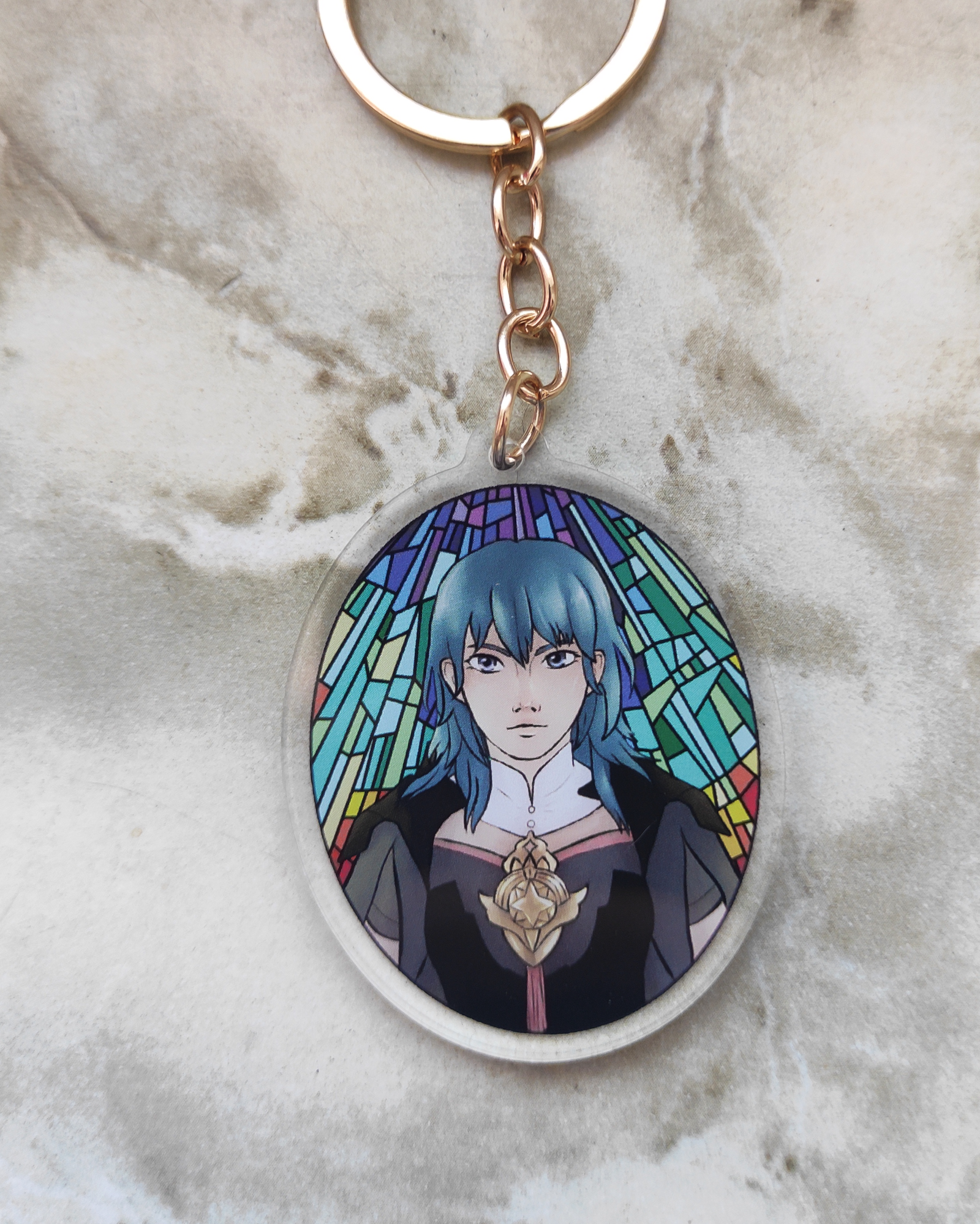 Keychain of Byleth from fire emblem on a marble surface.
