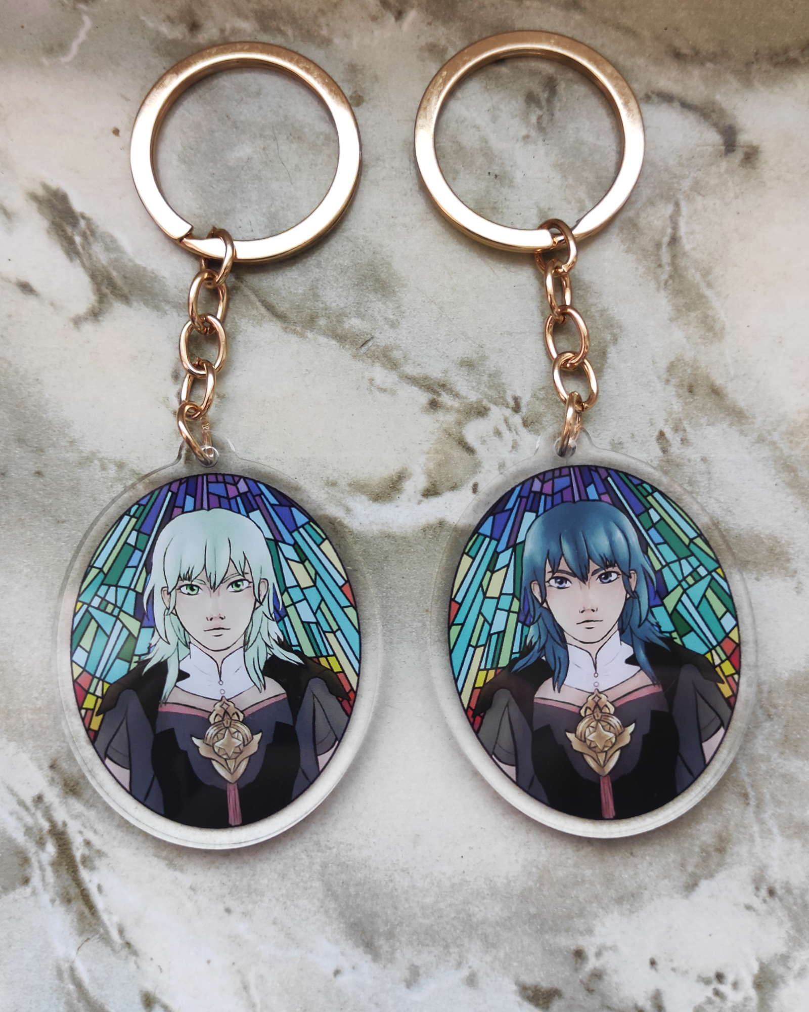 Two keychains of Byleth from Fire emblem. Each side shows a different version of her. 