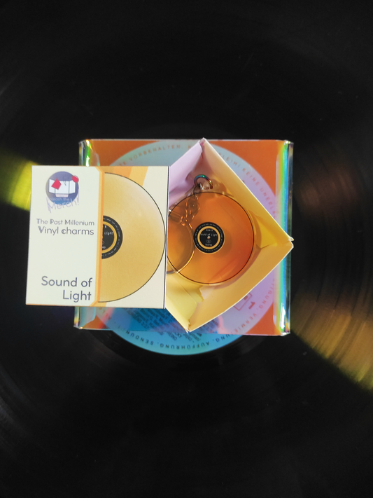 Yellow vinyl charm in packaging on a dark vinyl background